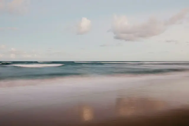 La mer calme sous un ciel pâle, des vagues douces sur le rivage
